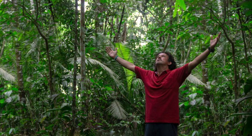 Young tourist man wearing red t-shirt raises his arms and looks up to the sky